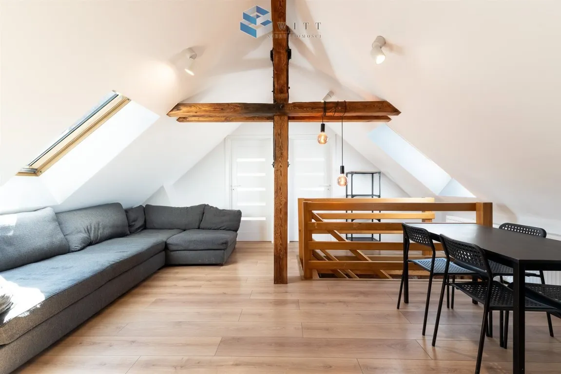 Restored two-level loft with brick walls and beams in Ostróda